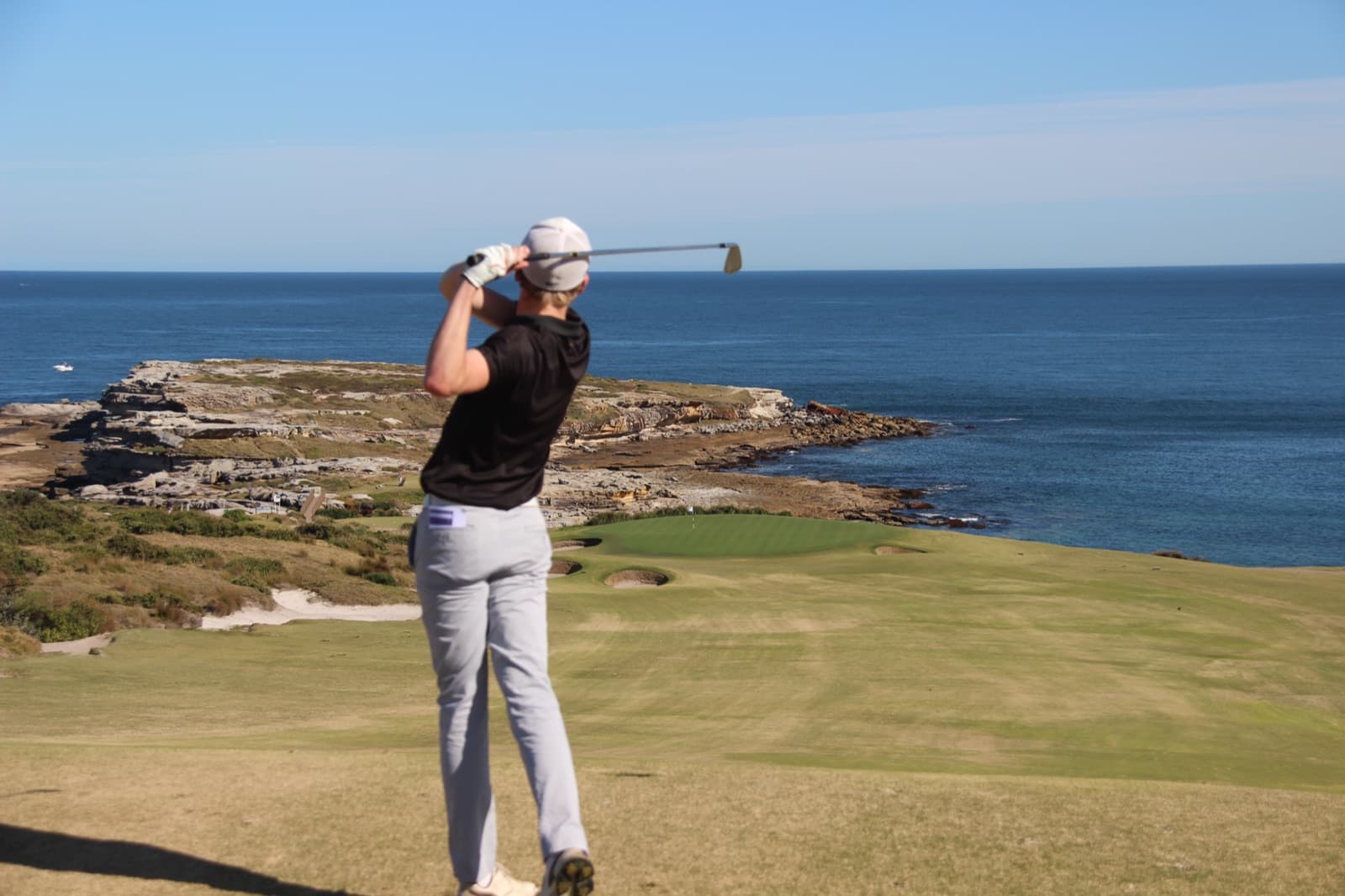 Golfer mid-swing on a coastal course